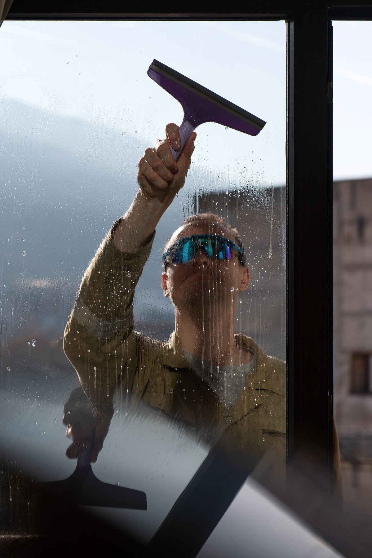 Worker performing exterior window cleaning using professional squeegee tool
